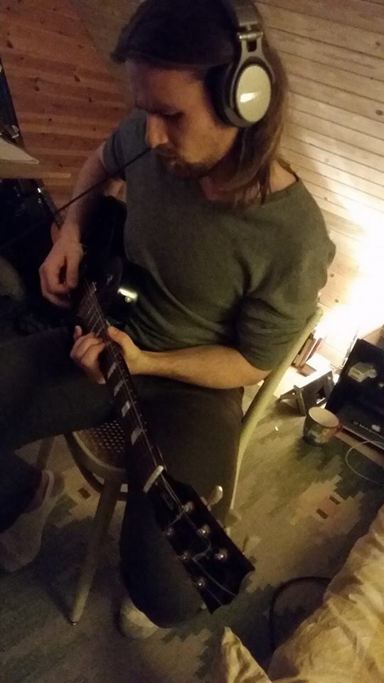 Axel with headphones playing guitar in the studio