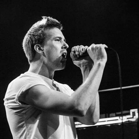 Axel singing into a handheld microphone on stage